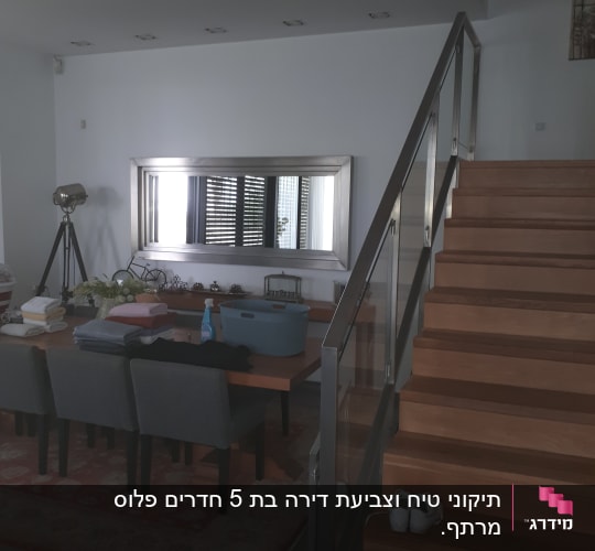 חדר עם שולחן, כיסאות, מדרגות וחפצים שונים